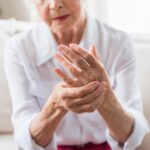 Foto de adulta tomándose una mano con la otra adolorida, en señal de Artritis Reumatoidea